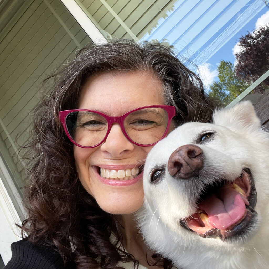 Michelle Ward smiling outside with her white dog Annie, both looking joyful in the sunshine.