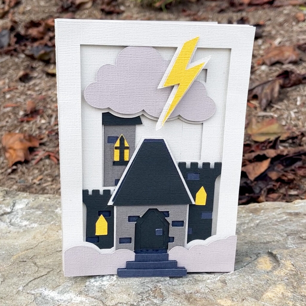 Layered paper castle shadow box card with clouds lightning bolt and gothic windows displayed outdoors
