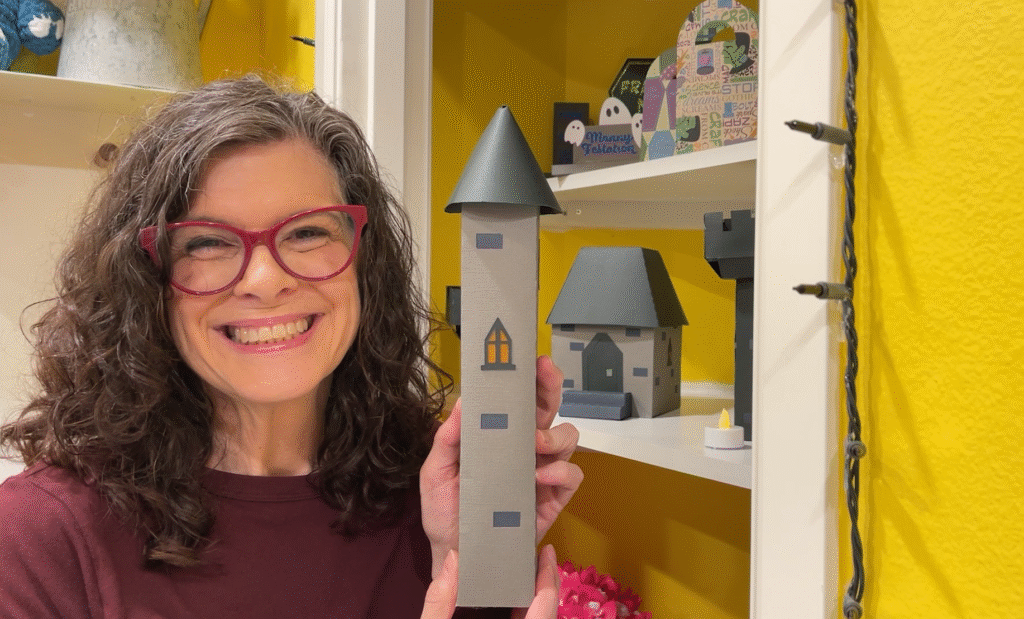 Michelle Ward smiling and holding the finished 3D paper tower craft.