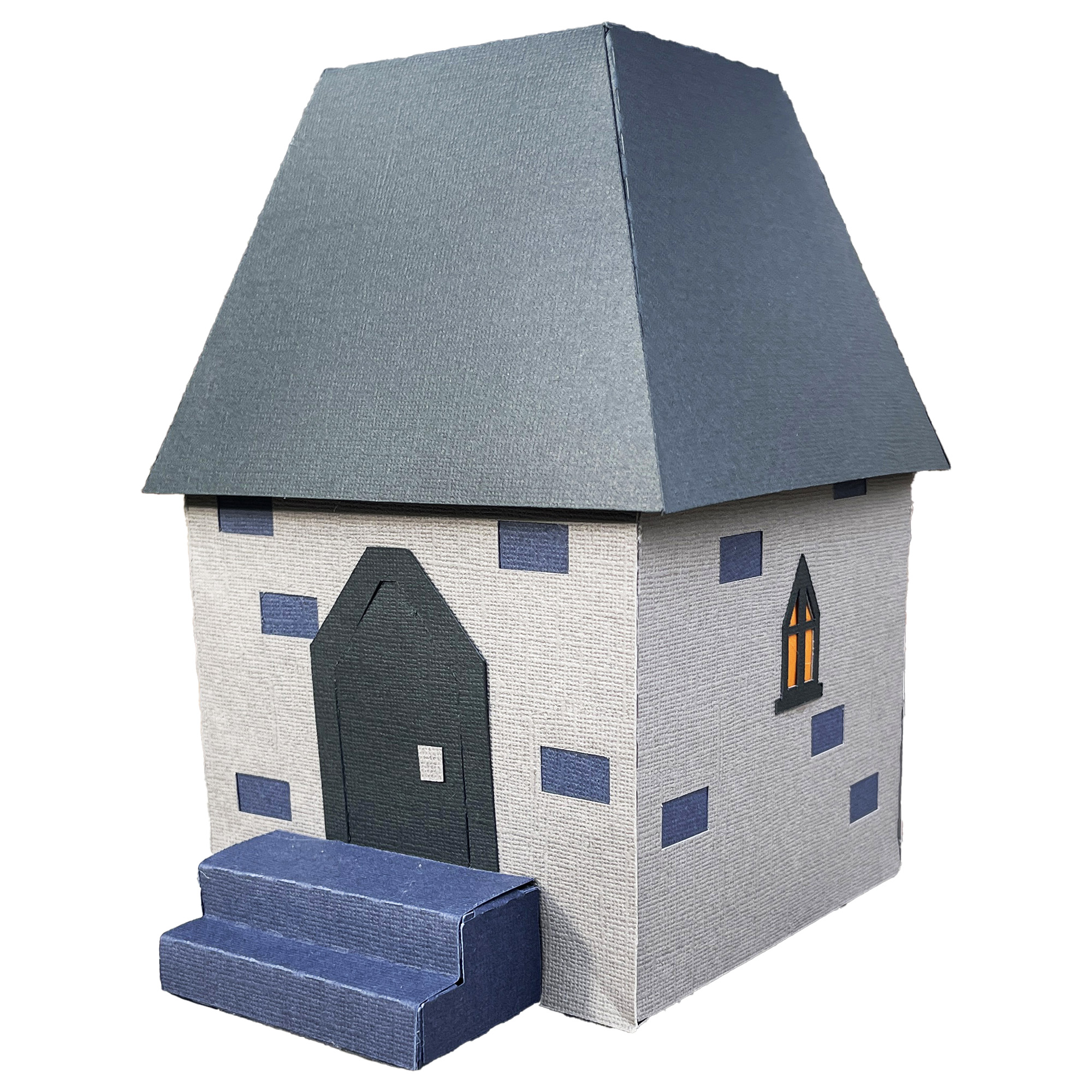 The finished Frankenstein Castle Gatehouse: a small square paper building in muted purple with a dark blue peaked roof, an arched door, and a short flight of steps leading up to it.