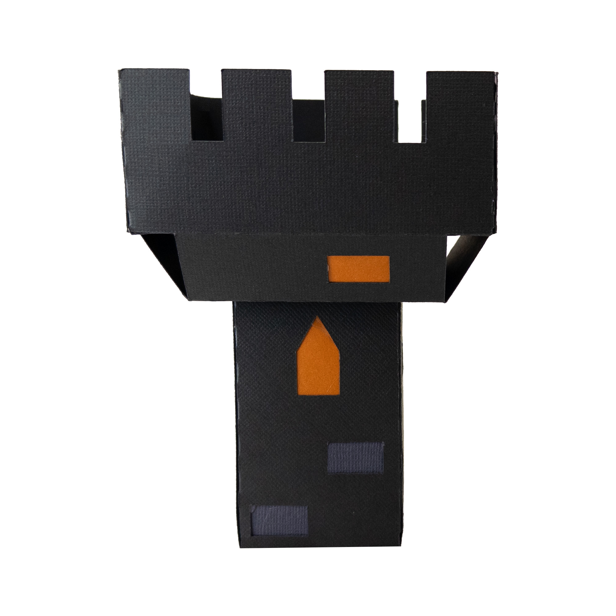 The finished Frankenstein Castle Short Battlement: a squat dark gray paper block with a notched battlement crown on top and a single window glowing orange.