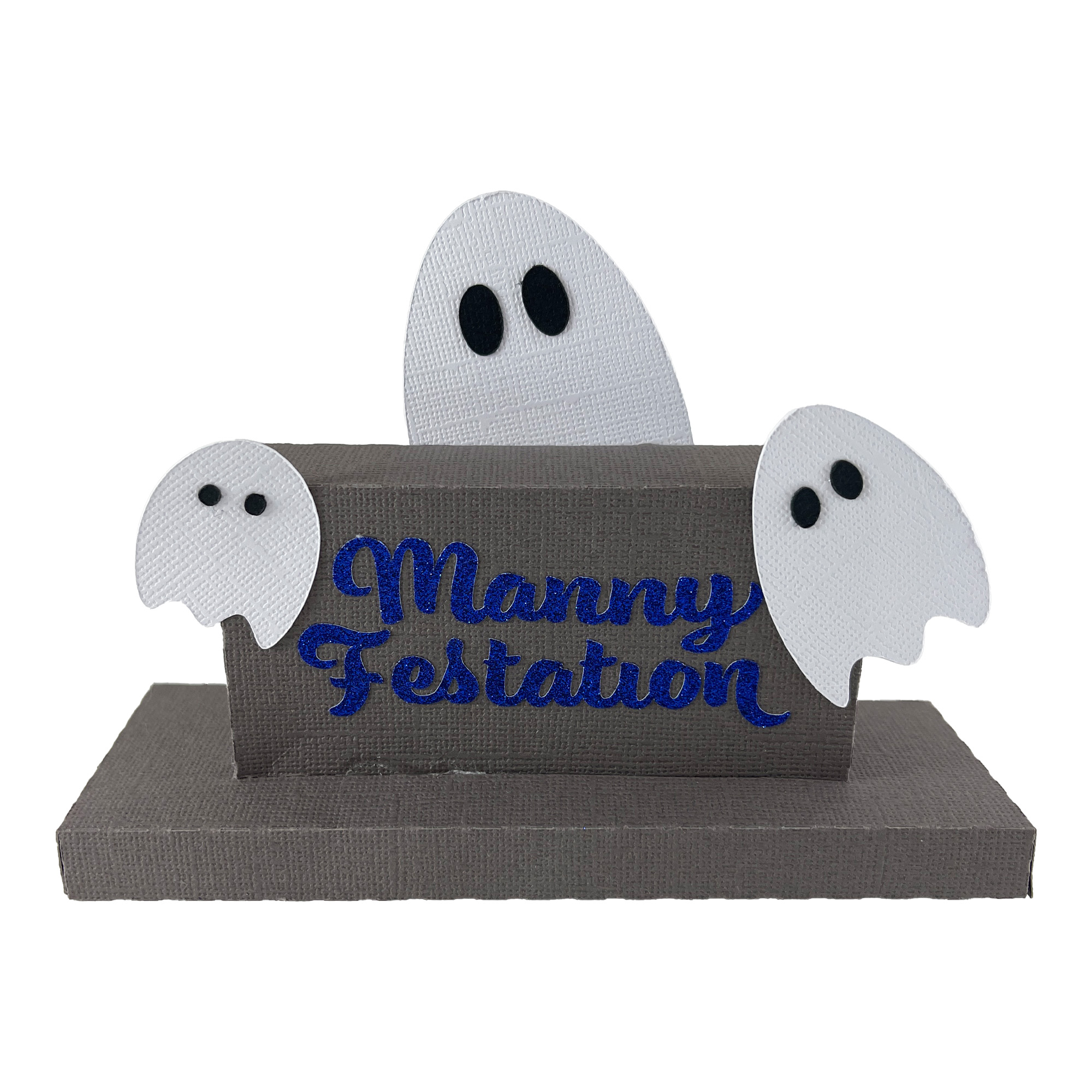 The finished Gravestone 4x2: a wide, low gray paper gravestone on a base, lettered in blue vinyl with the name Manny Festation, with three white paper ghosts peeking up behind and beside it.